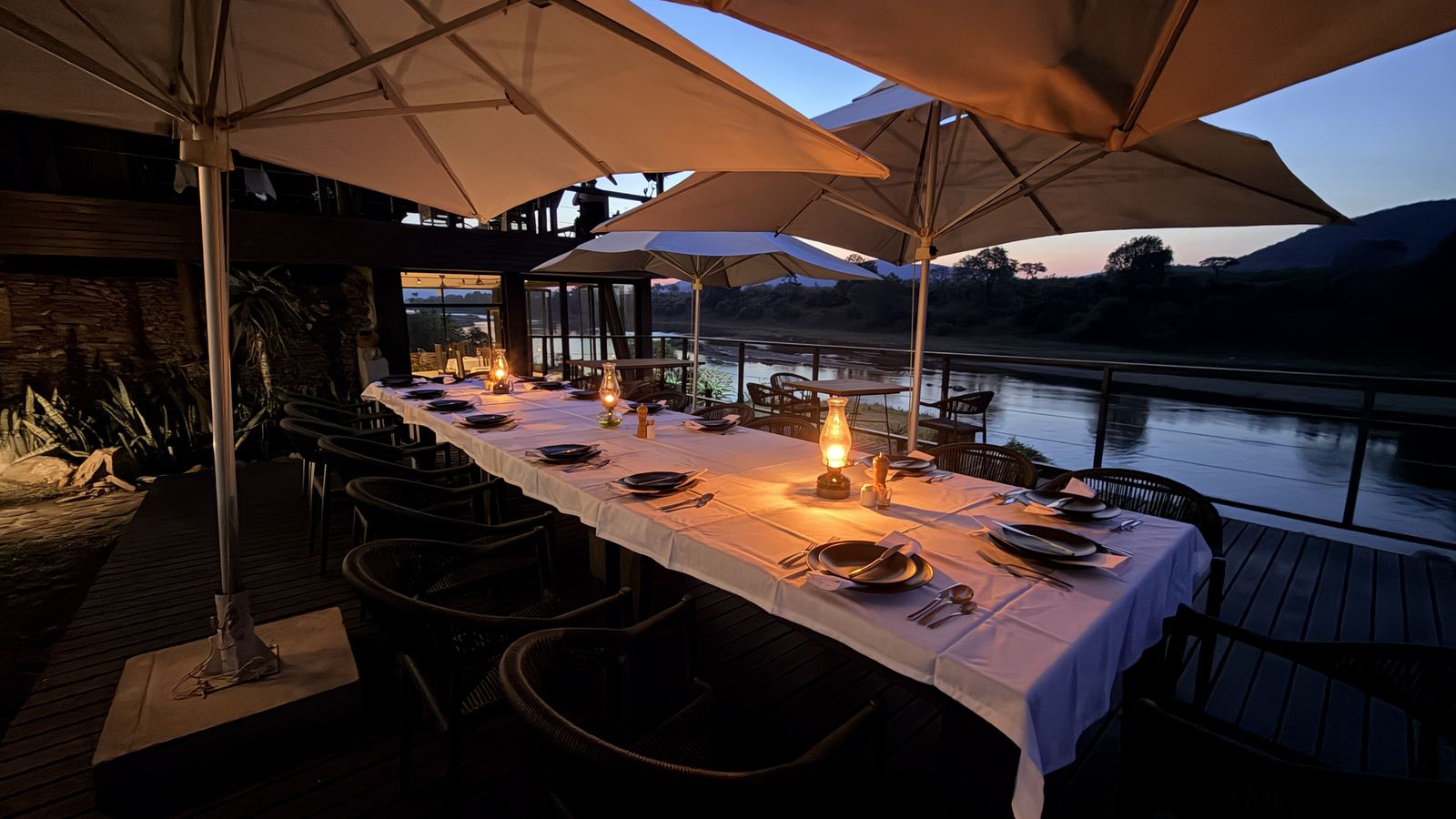 Dinner table with lanterns on the riverside deck at dusk