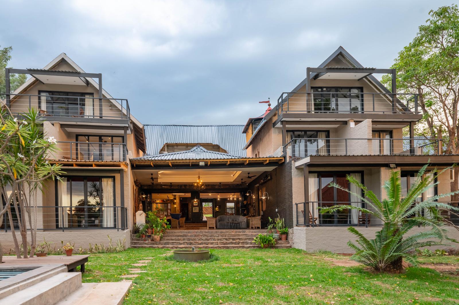 Two-storey thatched lodge buildings with lawn and deck