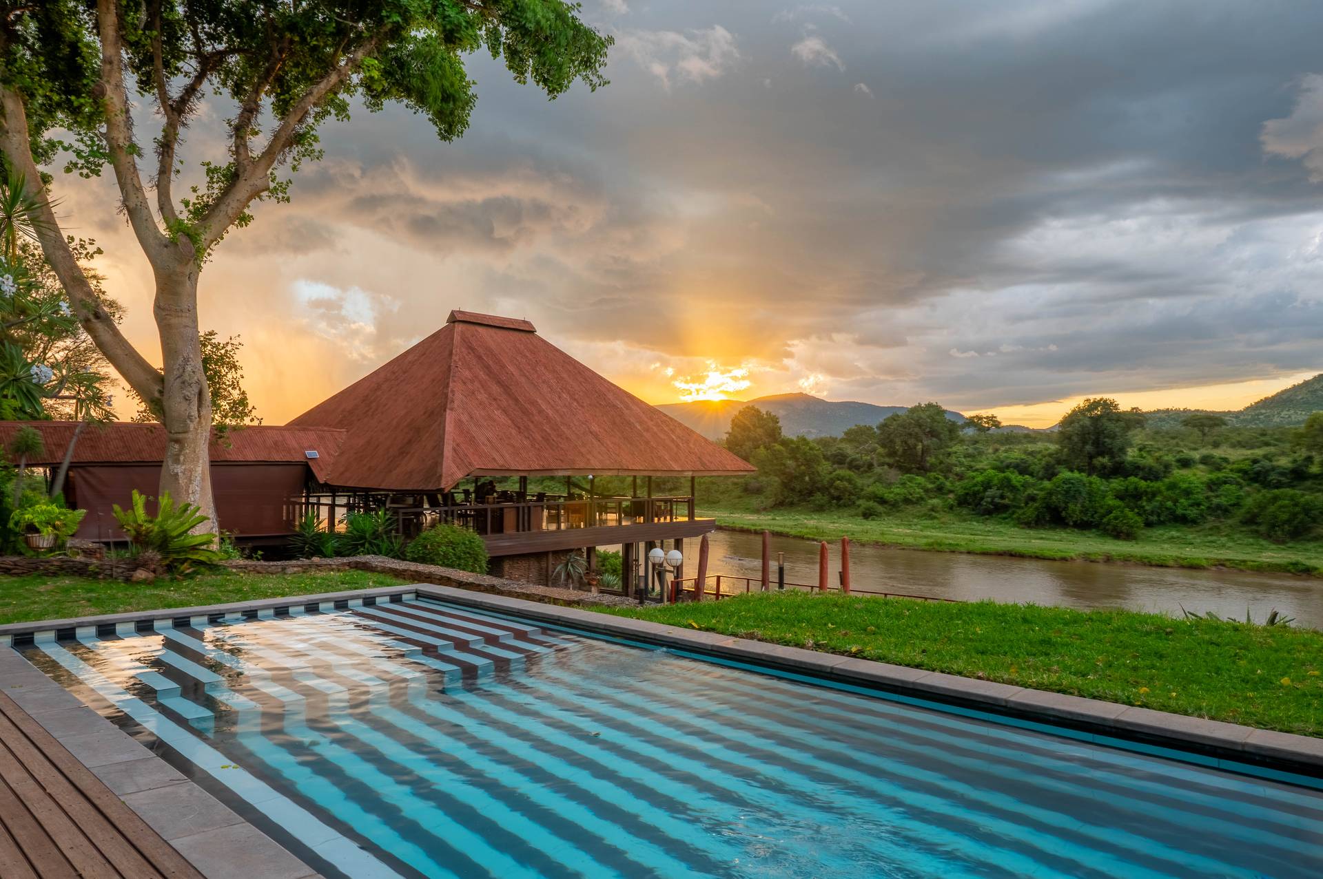 Lodge pool and thatched gazebo at sunset beside the Crocodile River